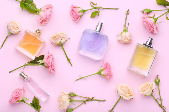 Perfume bottles with flowers on pink background