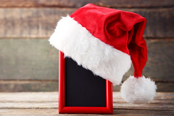 Obraz na płótnie Canvas Red santa hat with photo frame on grey wooden table