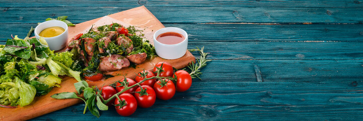 Fried sausages with potatoes and salad. On a wooden background. Top view. Copy space.