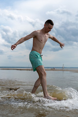 a young man goes in for water sports with skimboarding in shallow water on the shore