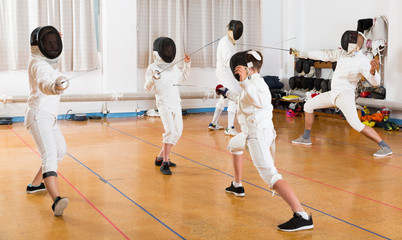 Adults and teens wearing fencing uniform practicing with foil