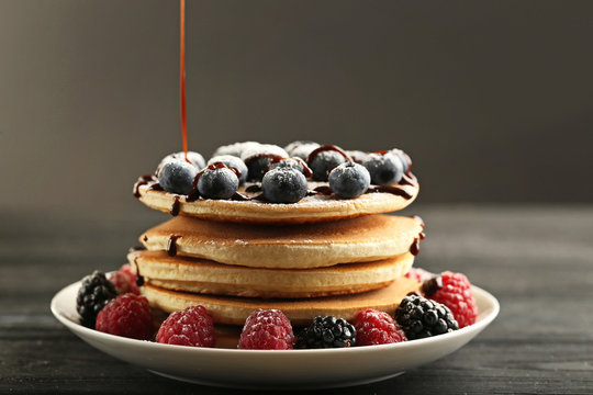 Tasty pancakes with berries on black wooden table