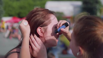 Girl paints Russian flag on her aunt's cheeck before game starts