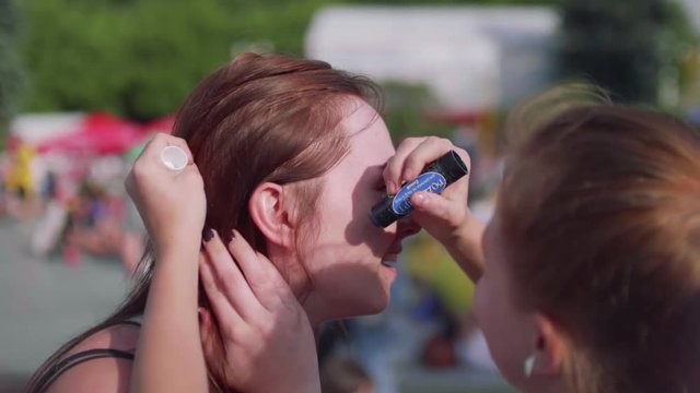 Girl paints Russian flag on her aunt's cheeck before game starts