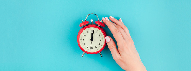 Woman hand holding the red vintage alarm clock