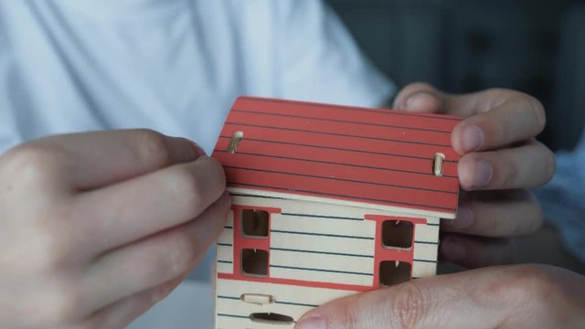 Mom and son sitting at a table gather a house from wooden blocks. Dream of a personal home. Playing and teaching children.