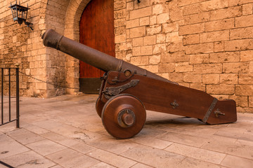 historische Kannone vor der Steinwand mit tor