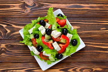 Greek salad on a wooden background. Space for text or design.