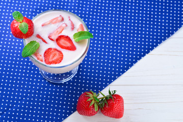 Homemade yogurt with fresh red strawberry on a wooden background. Top view.