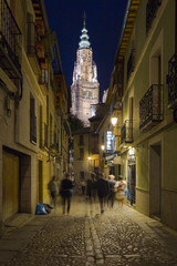 Naklejka na ściany i meble Vista de una calle de Toledo por la noche con la torre de la catedral al fondo