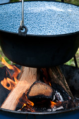 Fototapeta na wymiar detail of burning wood, fire in big metal kettle, preparation for cooking food in nature, campfire in nature close up 