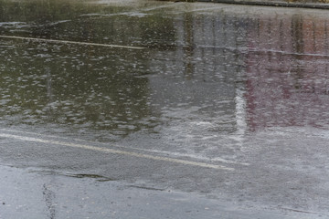 Heavy rain on a road, impact of drops, and reflexion.