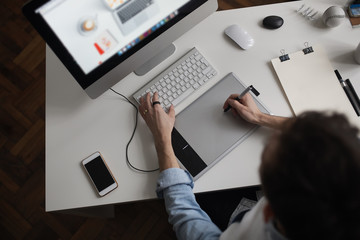 Young male designer using graphics tablet while working with com