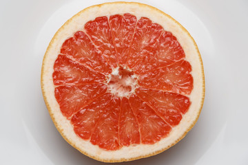 Fresh slice of red grapefruit on a white plate