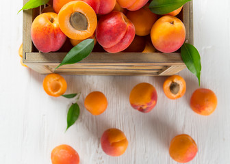Fresh apricots on a white wooden background.