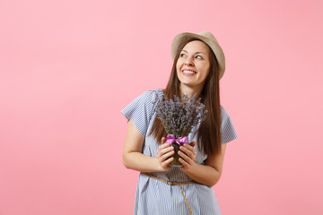 Portrait of a happy young tender woman in blue dress, hat holding bouquet of beautiful purple lavender flowers isolated on bright trending pink background. International Women's Day holiday concept.