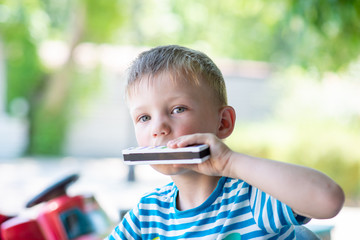 the boy plays the harmonica - obrazy, fototapety, plakaty