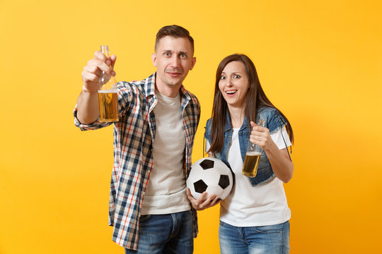 Young happy cheerful couple supporter, woman man, football fans cheer up support team, holding beer bottle, soccer ball isolated on yellow background. Sport, family leisure, people lifestyle concept.