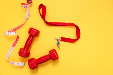 Two red dumbbells, tape measure and whistle