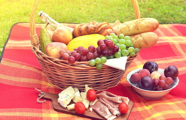 Basket with Food Fruit Bakery Cheese Ham Tomato Picnic Green Grass Summer Time Rest Background Toned Photo