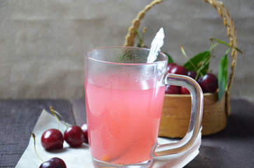 Kissel with cherries in a glass on an old wooden background, traditional russia or poland drink, berry jelly, mousse, summer pink drink,