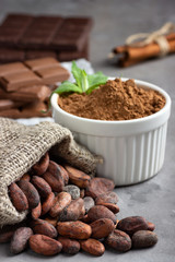 Cocoa beans, powder and chocolate on gray stone background.