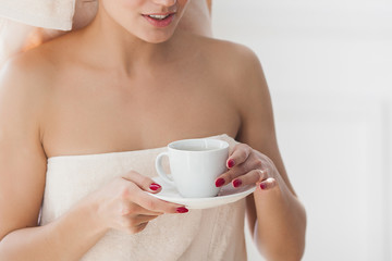 Beautiful woman in the towel after bathing drinking morning coffee