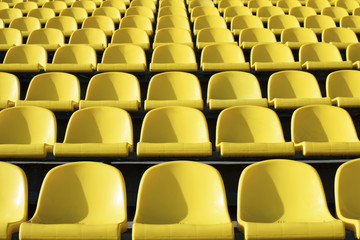 Fototapeta premium Empty plastic yellow seats at stadium, open door sports arena.