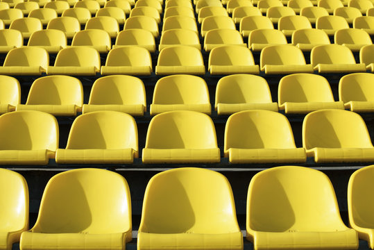Empty plastic yellow seats at stadium, open door sports arena.