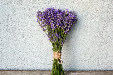 Bouquet of lavender on an old wooden table on a cracked white background.
