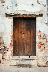 A wooden door in a run down old building with lots of detail.