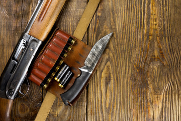 Hunting rifle and ammunition lie on wooden background. Copy space