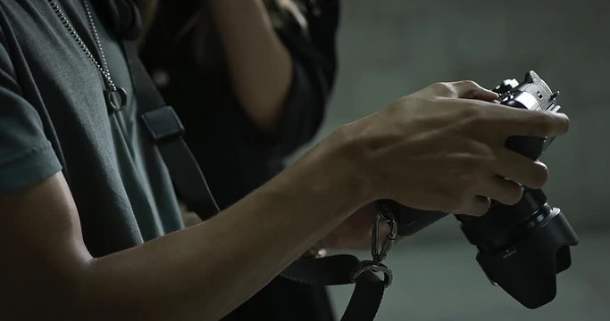 Handheld slow-motion close up footage of photographer holding camera while model looks and points