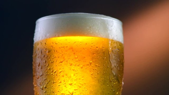 Cold beer in a glass with water drops. Craft beer closeup. Rotation 360 degrees. 4K UHD video 3840x2160