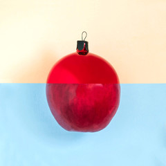 Christmas ball and apple are connected on two-color background