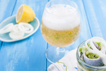 Traditional Dutch marinated herring with lemon and onions in a jar. Fresh Belgian beer in a glass....