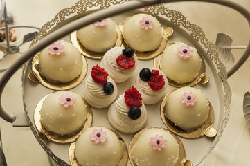 Candy bar presentation/Arrangement of assorted chocolate cookies with vanilla frosting and meringues with cream and berries on a special tray.