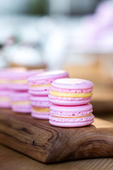 pink macaroon with lemon filling lie on a wooden board.