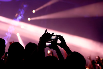 People take pictures with point and shoot cameras and cell phones at a rave party concert