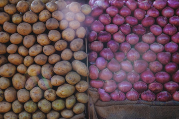 Fresh indian vegetables stored on market stalls: red onions and potatos