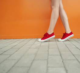 Girl wearing trendy red shoes. Shoes close up shoot in front of orange wall for fashion store