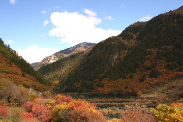 Hiking through the Min Mountains, surrounded by the colorful fall foliage in Jiuzhaigou Valley National Park of Sichuan, China.