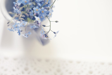 Bouquet of blue forget-me-nots in a cup on a lacy tray, the top view.