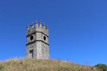 Fototapeta premium Old dovecot, old watchtower on hill against clear blue sky with space for copy