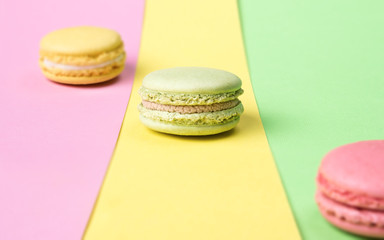 Yellow, green and pink macaroons on colorful background