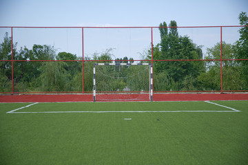 Mini Football Goal On An Artificial Grass . football goal on a green lawn . Football field near fence at day sunny day