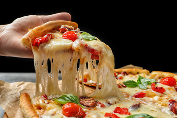 Woman holding slice of delicious hot pizza over table, closeup