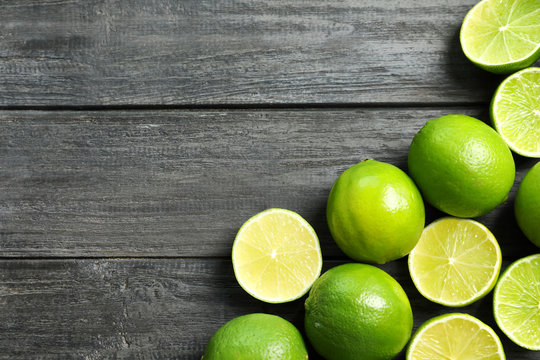 Composition with fresh ripe limes on wooden background, top view