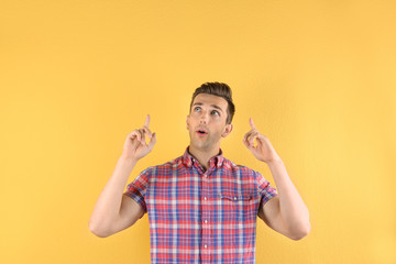 Handsome emotional young man on color background