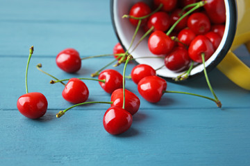 Obraz na płótnie Canvas Metal mug and ripe red cherries on wooden table, closeup